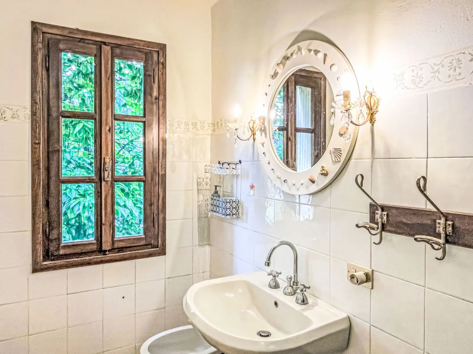 Helles Badezimmer mit Waschbecken, Spiegel und Holzfenster